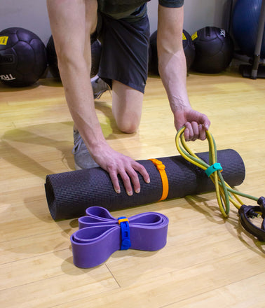 Gym fitness workout equipment including exercise mat, strength bands and jumprope are secured and with Packbands
