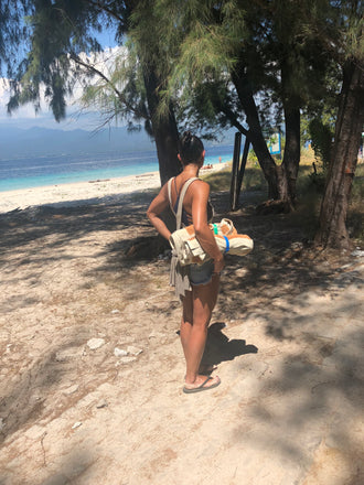 A woman at the beach on vacation using Packbands to hold rolled beach towels