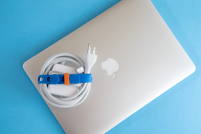 A laptop computer and charging cable cord stored with a Packband to keep it tidy